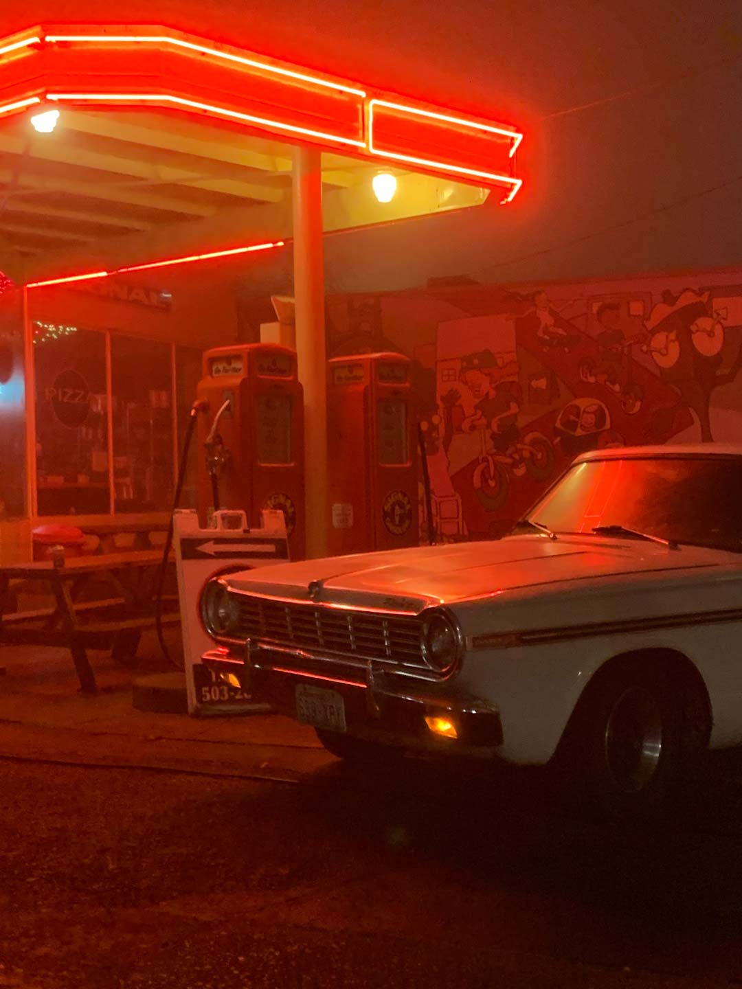 Vintage car and gas station with a red background.